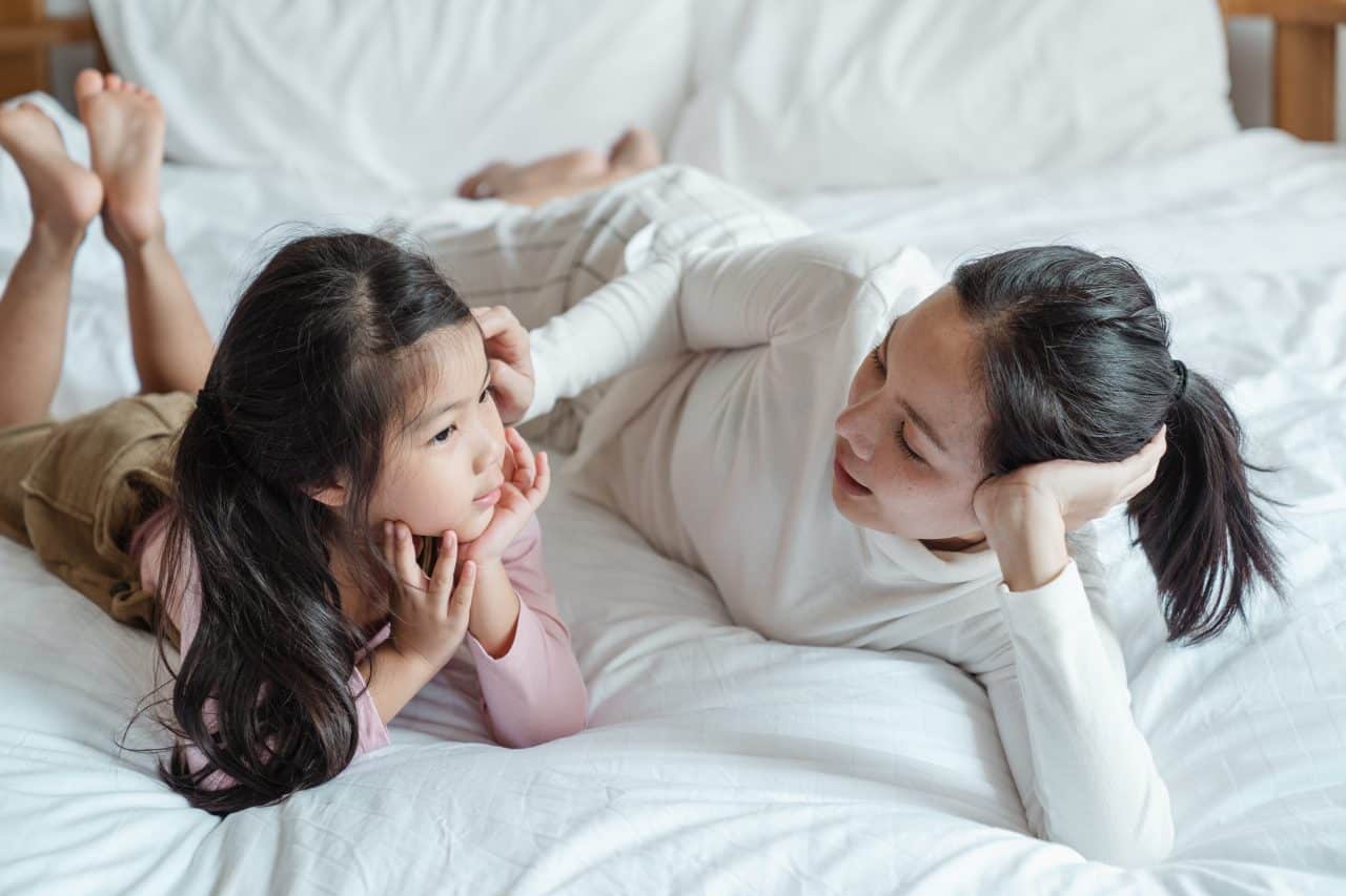 Mother talking with her daughter in bed.