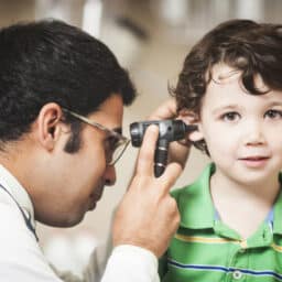 Toddler-aged boy getting an ear exam as part of a hearing test.