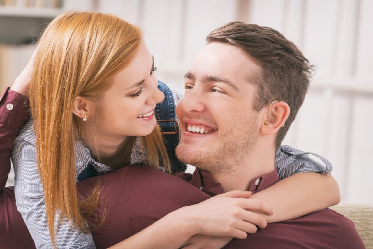 Man with hearing aids getting hug from his girlfriend or partner.