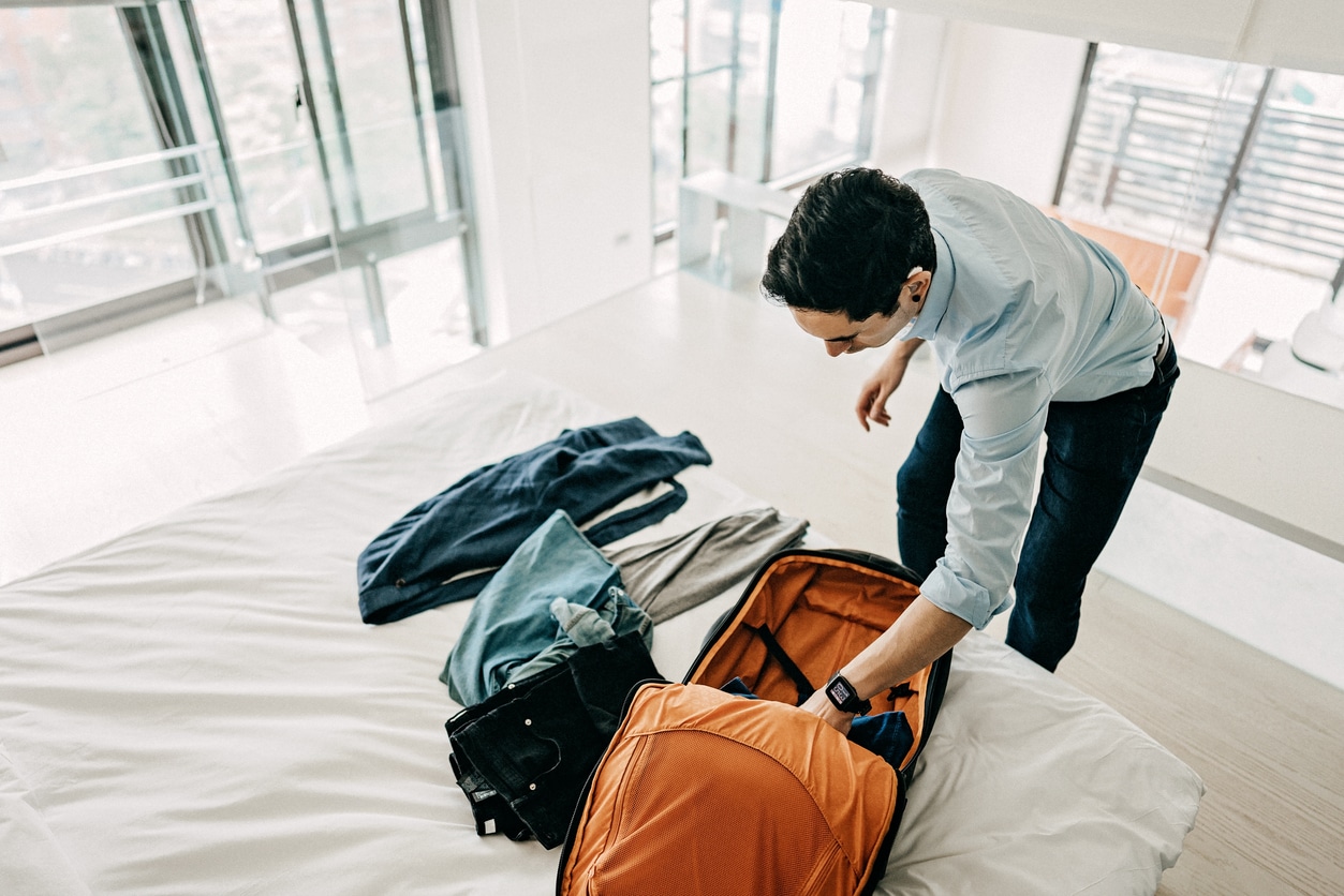 Man wearing a hearing aid packing a suitcase.