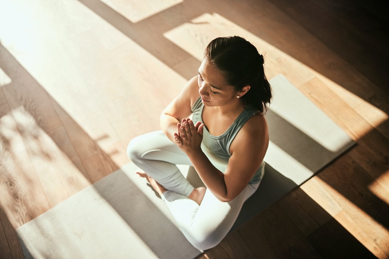 Woman on yoga mat sitting cross-legged meditating