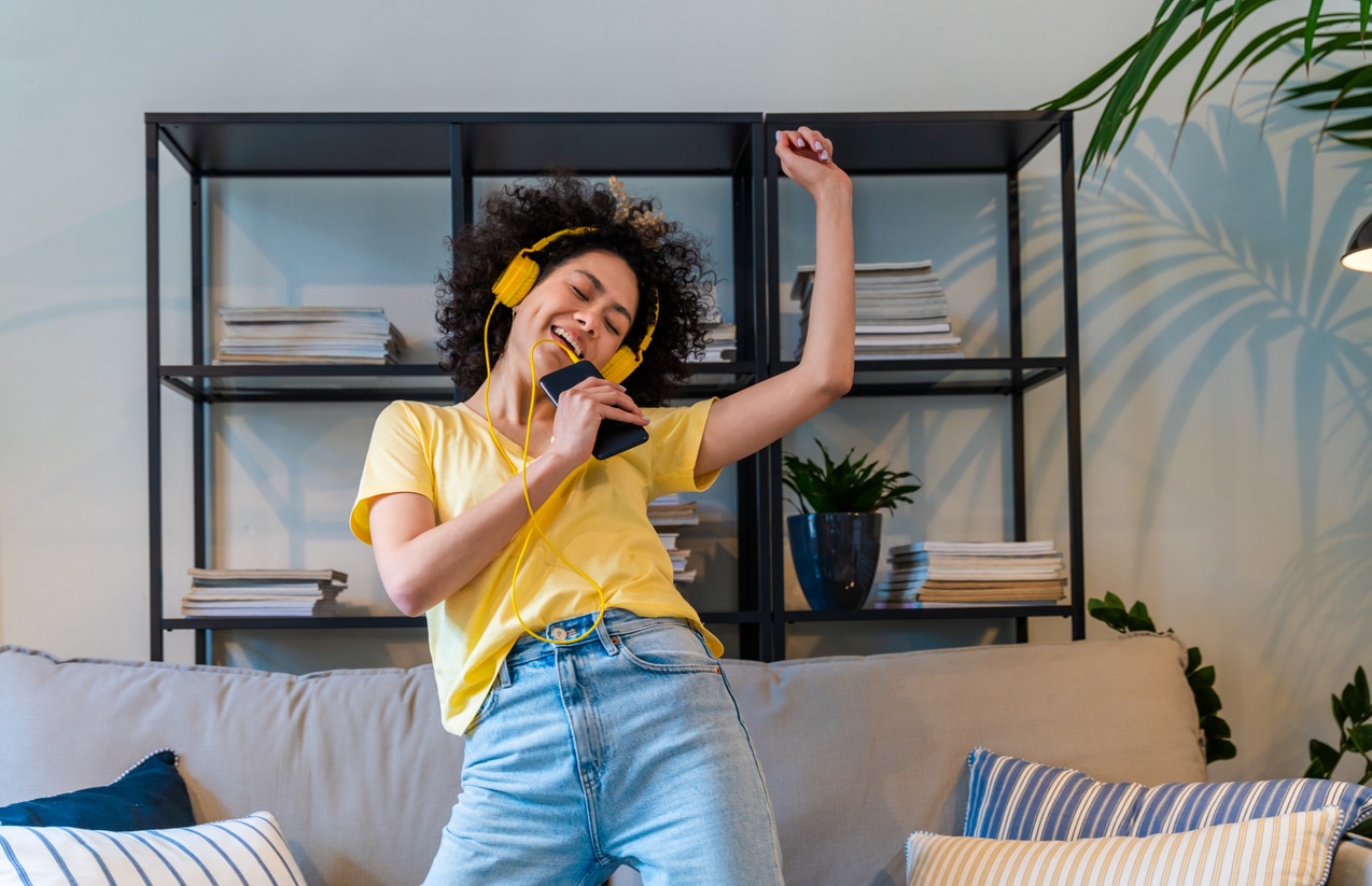 Woman listening to music dancing on her couch