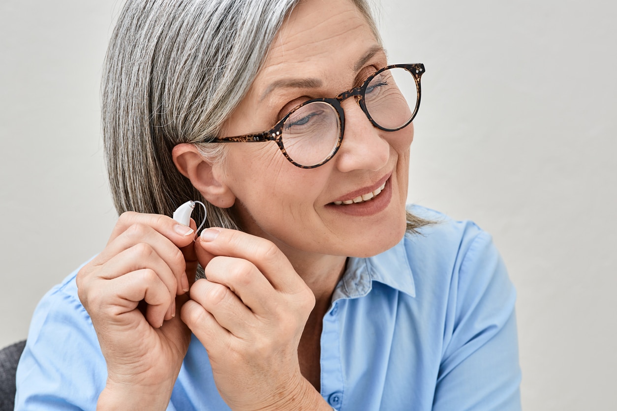Woman putting on a hearing aid.