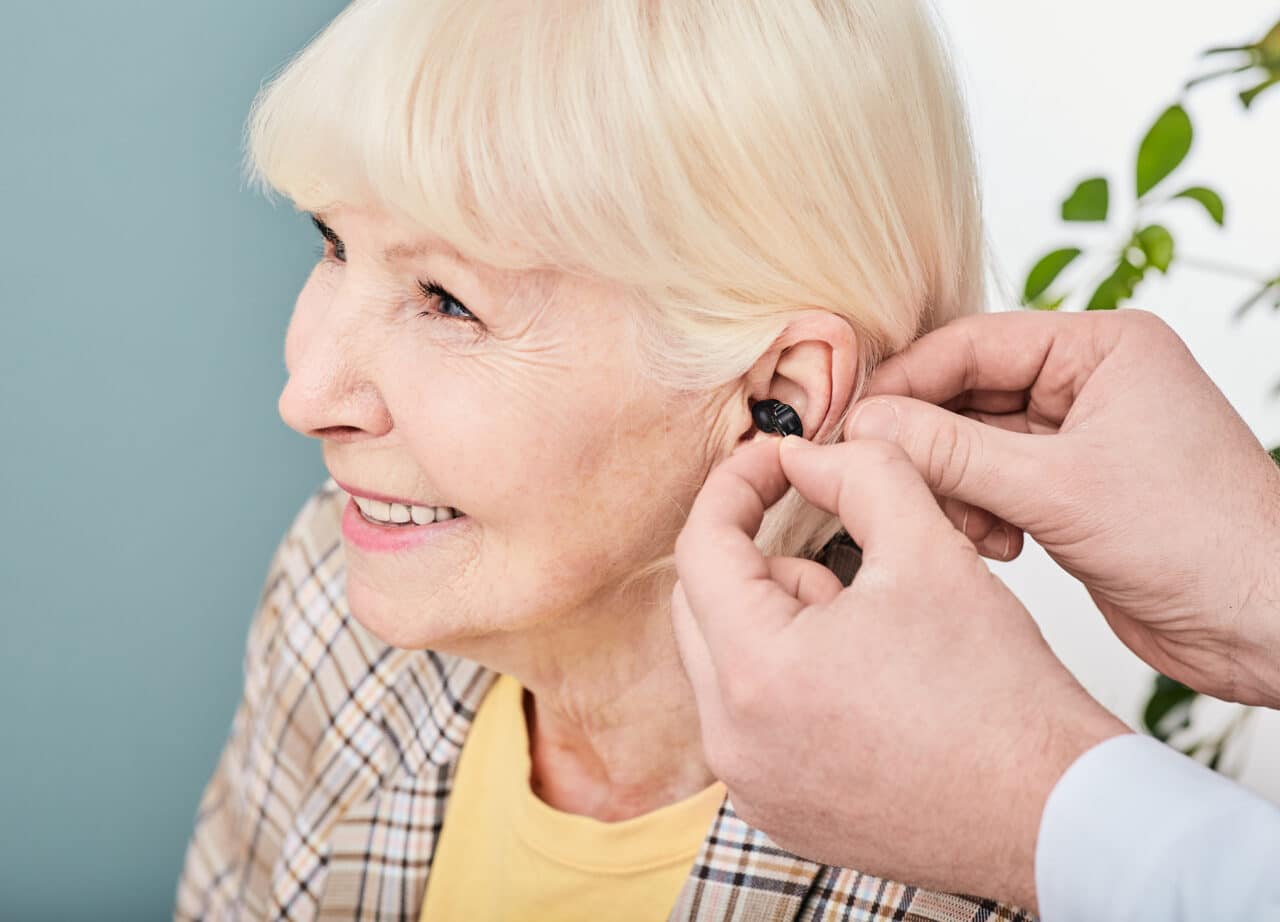 Smiling senior woman being fitted for hearing aids.