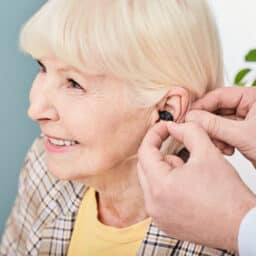 Smiling senior woman being fitted for hearing aids.