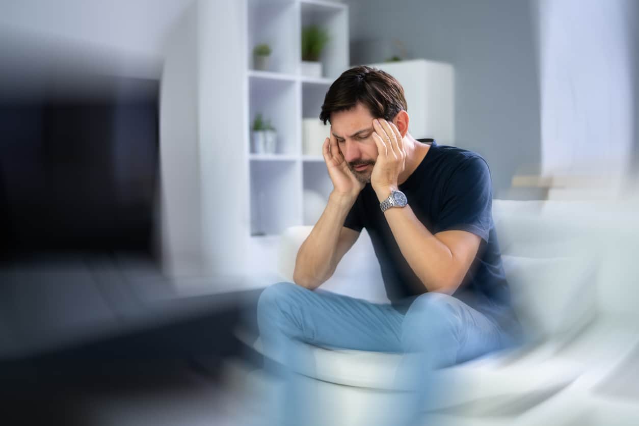 Man experiencing tinnitus holding his head.