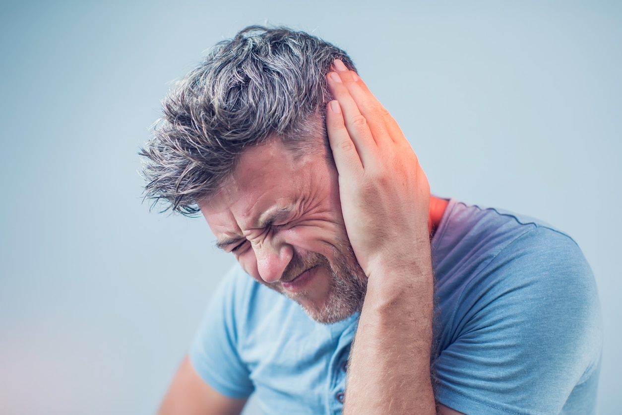 Man with tinnitus holding his left ear. 