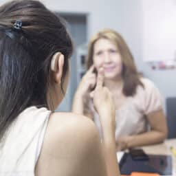 Young woman giving a thumbs up for her new hearing aid