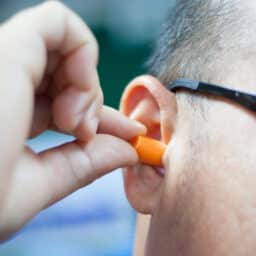 Man putting an earplug into his ear.