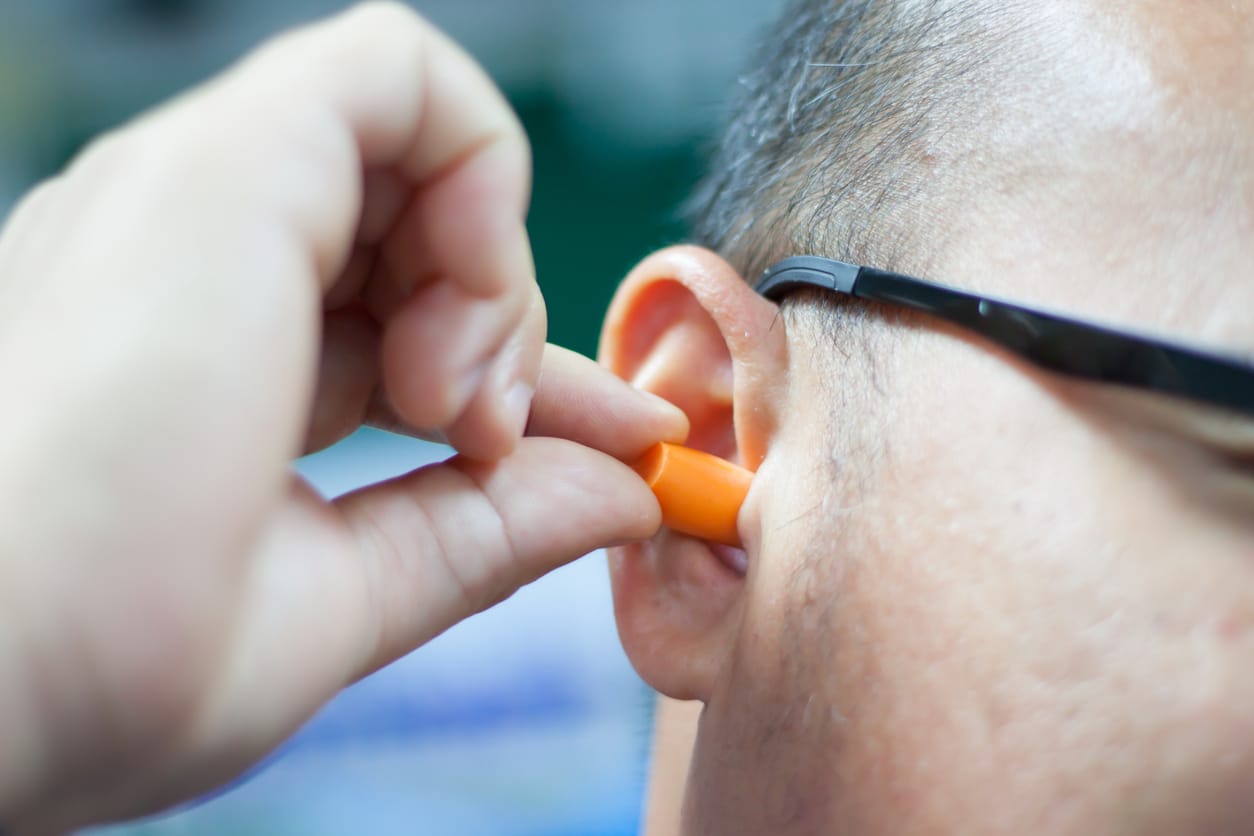 Man putting an earplug into his ear.