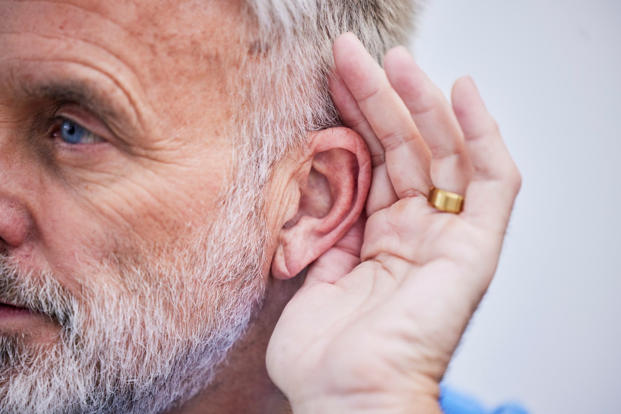 Man holds hand behind ear to hear