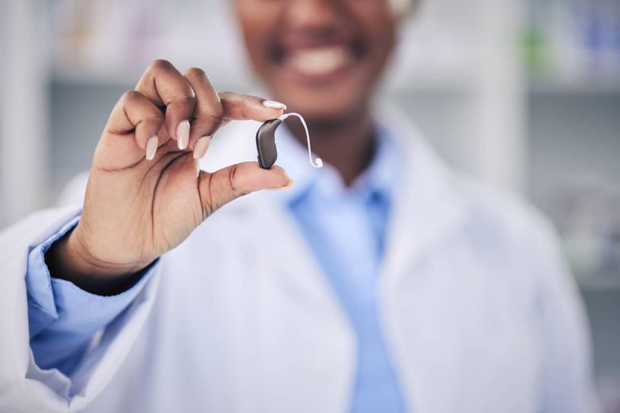 Audiologist holding up a behind-the-ear hearing aid.