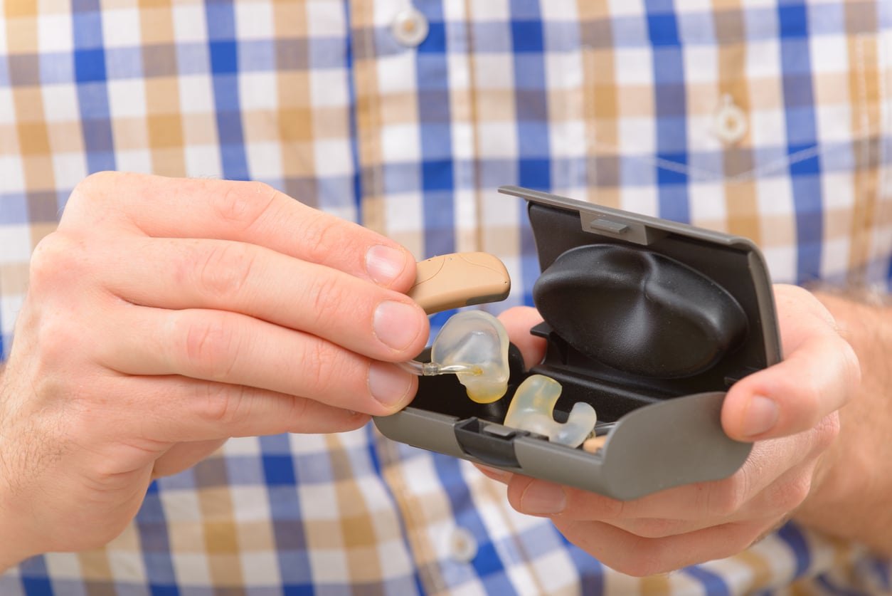 Closeup of a man holding his new hearing aids.