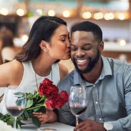 Woman kisses her partner at Valentine's Day dinner with roses