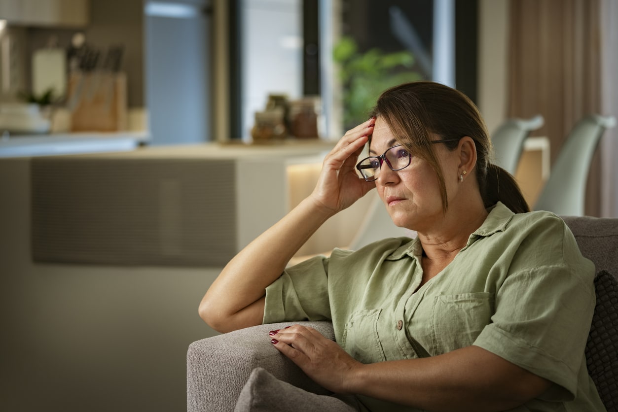 Stressed woman sitting on her couch at home.