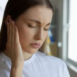 Woman with tinnitus holding her right ear