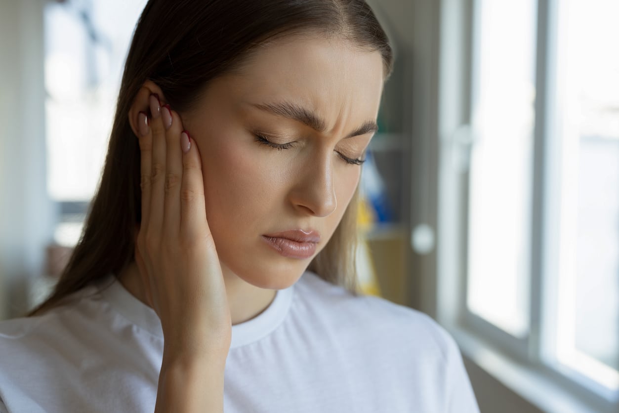 Woman with tinnitus holding her right ear.