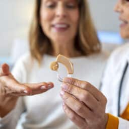Audiologist showing a hearing aid to her patient